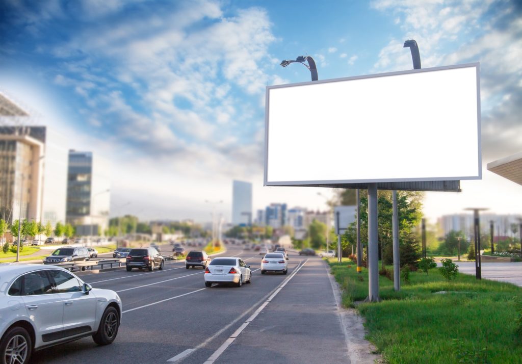 Billboard canvas with city in the background. Beautiful summer sky behind it.