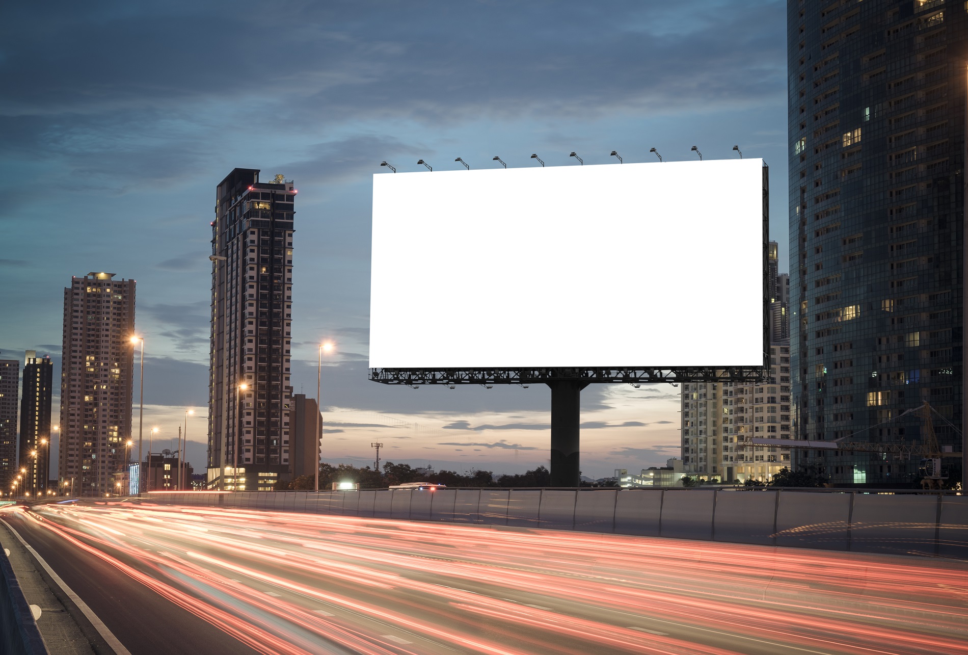 Blank billboard on the highway during the twilight with city background