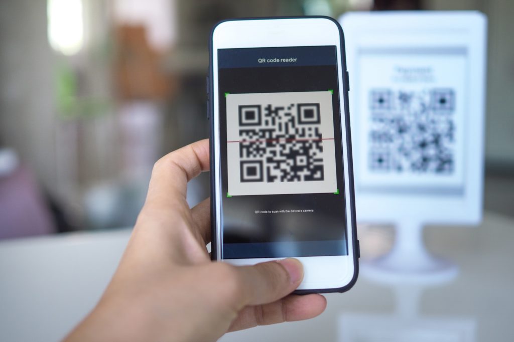 Women's hand uses a mobile phone application to scan QR codes in stores that accept digital payments