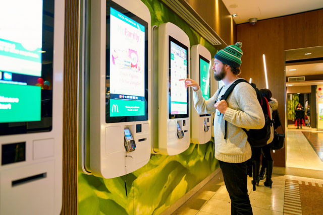 customer at a McDonald's store place orders and pay through self ordering kiosk